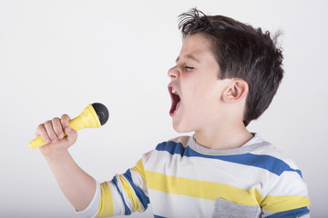 niño cantando con un micrófono - obrazy, fototapety, plakaty