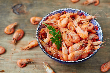 Fresh shrimps on a blue bowl on a wooden background