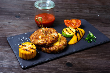 two fried cutlets next to peppers and tomatoes