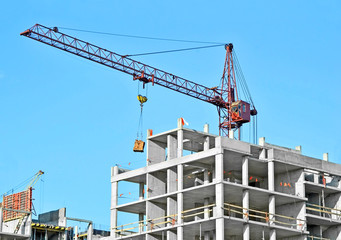 Crane and building construction site against blue sky