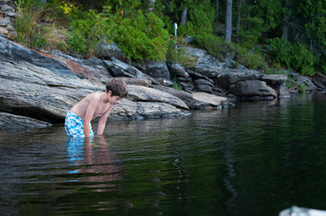 boy child standing in a lake looking into the water