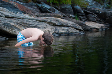 boy child standing in a lake looking into the water