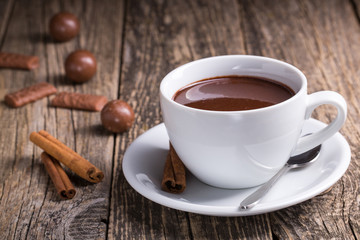 White cup of delicious hot chocolate with candies on table.