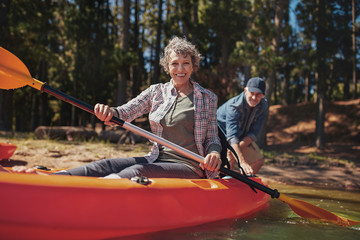 Happy senior woman in a kayak at the lake