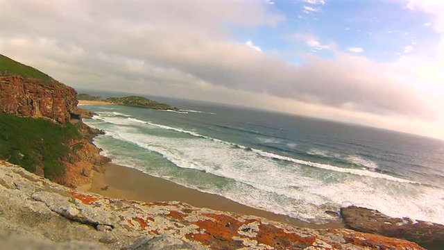 View from the cliffs at sunset. Robberg Nature Reserve, Plettenberg Bay, South Africa. Beach, waves and seal colony on the horizon .