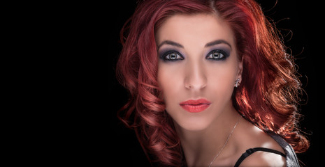 Glamour shot of a very nice redheaded lady on a black background with copy space