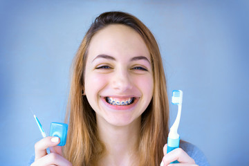 Beautiful smiling girl with retainer for teeth brushing teeth .