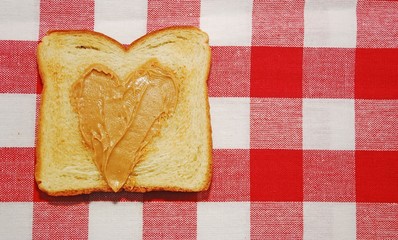 Peanut butter spread in a heart shape on a piece of toast