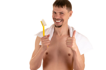 smiling adult naked man with big bright yellow toothbrush in his right hand raised and the thumb on left hand with white towel on his shoulders