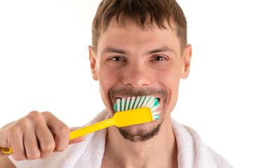 portrait of adult smiling man with big yellow toothbrush in hand and white towel on his shoulders