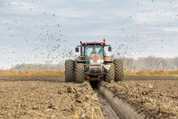 Tractor with double wheeled ditcher digging drainage canal