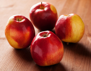Four red apples on a wooden table closeup shot
