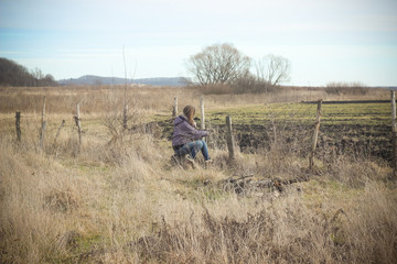 Obraz premium Beautiful young girl posing in autumn cold field iin winter clot
