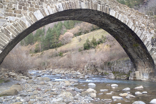Single-span stone bridge crossing a water stream.