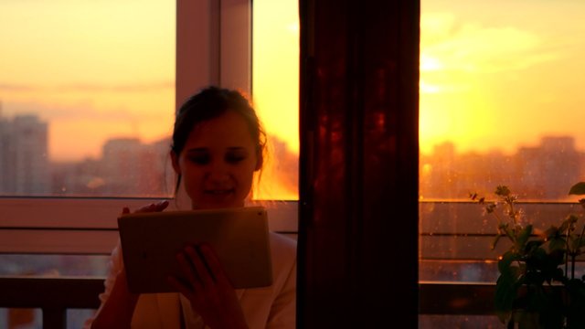 woman using tablet with sunbeams and lens flare Business girl young adult against sunset sky window on blurred city background. 4k