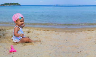 Little baby girl playing on the summer beach