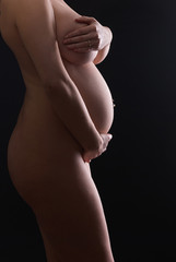 Proud and attractive pregnant mother posing at studio professional shadow shoot for naked pregnancy body art