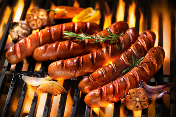 Sausages on the barbecue grill with flames - obrazy, fototapety, plakaty