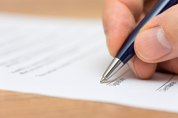 closeup of pen and human fingers  signing document