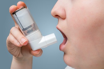 Asthmatic woman suffers from asthma and holds inhaler in hand. - obrazy, fototapety, plakaty