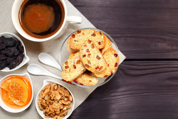 Homemade biscotti are laid out in the form of words next to a large cup of hot black coffee on vintage rustic table