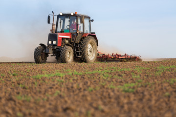 Tractor cultivating field at spring