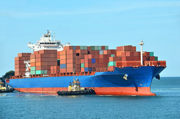Tugboat assisting container cargo ship