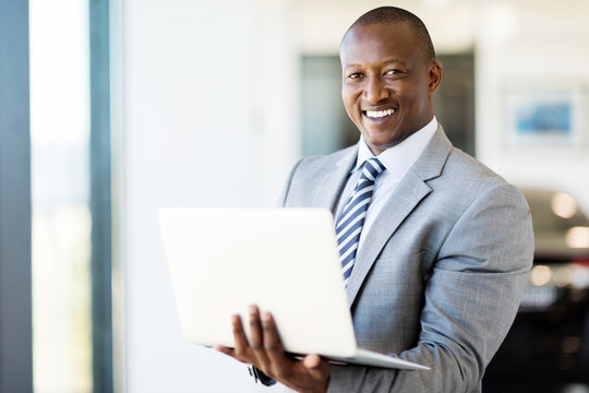 Afro American Vehicle Sales Consultant Using Laptop