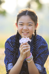 thai 12s years girl sitting on garden field with pink flowers in