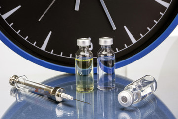 medicine vials and syringe, the clock shows the time of the medi