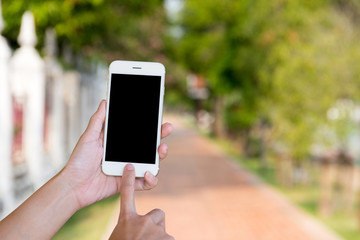 Hands woman are holding touch screen smart phone,tablet on blurred walkway garden nature background.