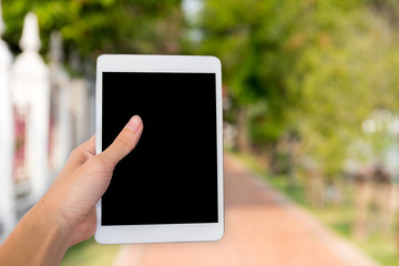 Hands woman are holding touch screen smart phone,tablet on blurred walkway garden nature background.
