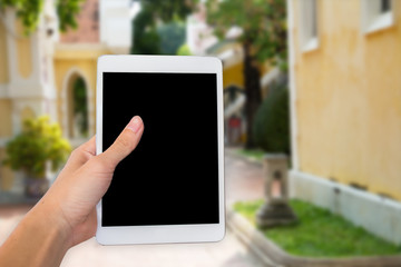 Hands woman are holding touch screen smart phone,tablet on blurred road and building with nature background.
