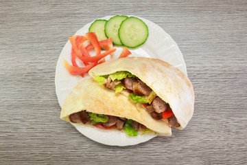 Falafel and fresh vegetables in pita bread on wooden