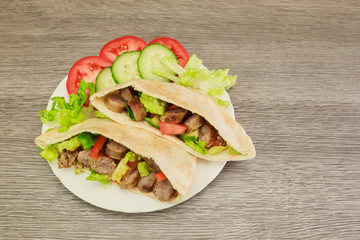 Falafel and fresh vegetables in pita bread on wooden