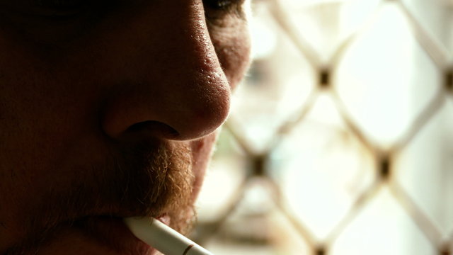 Unshaven man lighting cigarette, dramatic light