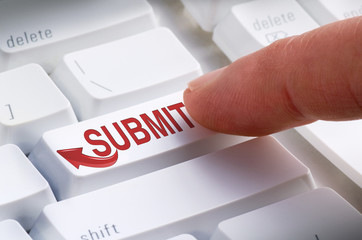 Closeup of a big SUBMIT button on a keyboard with a finger getting ready to hit it and make a...