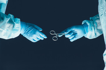 Two surgeons working and passing surgical equipment in the operating room