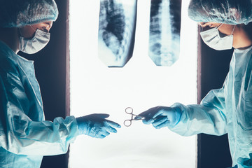 Two surgeons working and passing surgical equipment in the operating room