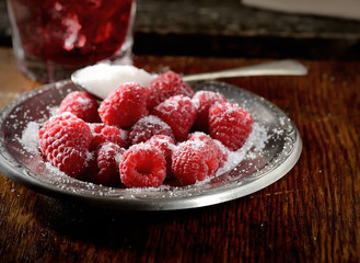 raspberries with sugar on wooden background