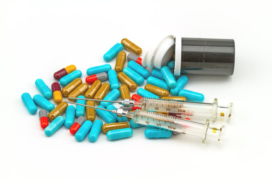 colorful pills , syringe and black bottle tablets on white background