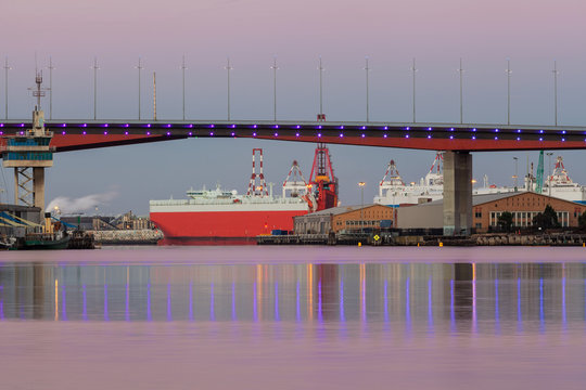 Closeup of section of Bolte bridge in Melbourne and a large red cargo ship in early morning. - Powered by Adobe