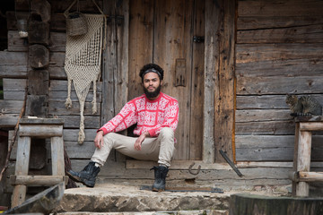 portrait of young hipster in front of wooden house