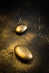 Deux galets en or sur un fond doré et noir format verticale