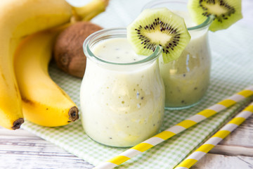 Banana smoothie with kiwi and oats on a light wooden table. Healthy food
