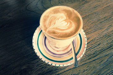 Latte in a cup on a wooden table - vintage effect