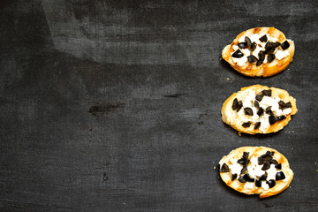 Bruschetta with feta and black olives on a black background.