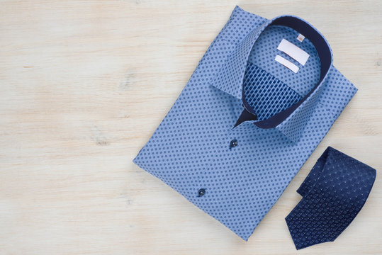 Folded blue man shirt and tie isolated on wooden background