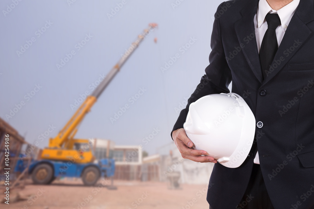 Wall mural engineer holding helmet with construction crane background