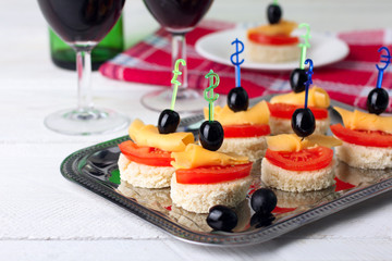 delicious canapes on iron dressing on a white wooden background near the wineglasses with wine